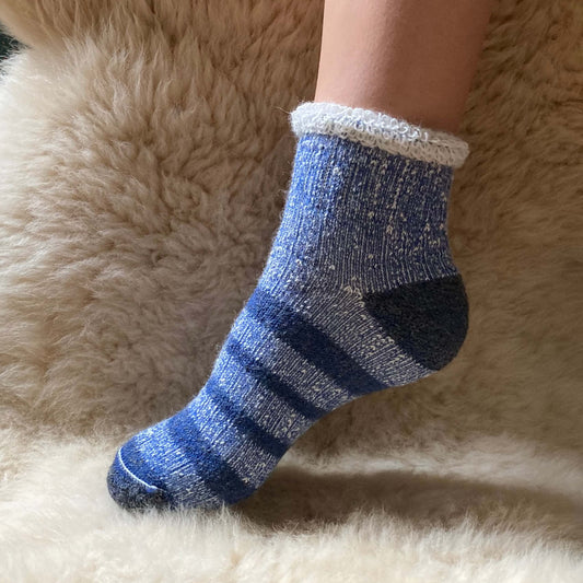 Ankle length blue striped alpaca sock on a fluffy surface