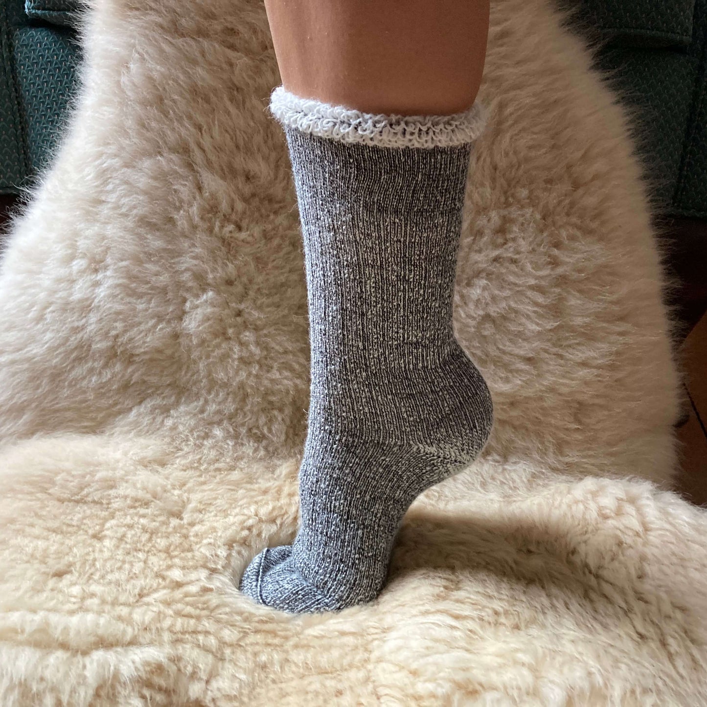 Heavy weight grey alpaca sock on a fluffy beige surface