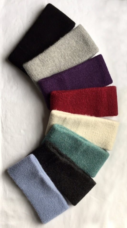 Eight knit alpaca headbands in black, grey, purple, burgundy, ivory, seafoam, charcoal, and powder blue.