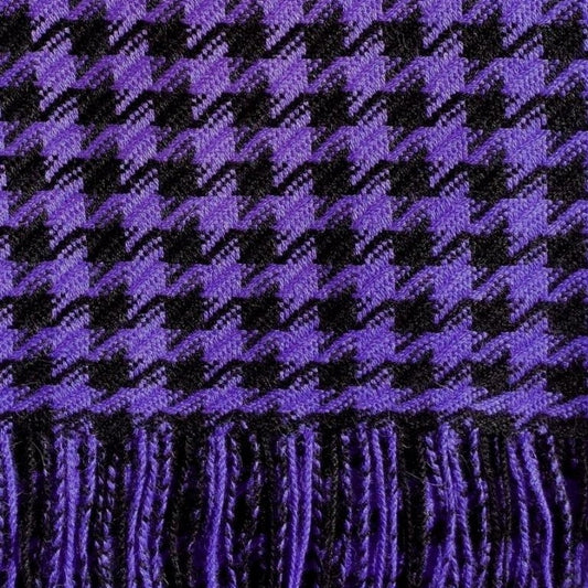 A close-up of a periwinkle purple and black houndstooth patterned fabric with fringed edges.