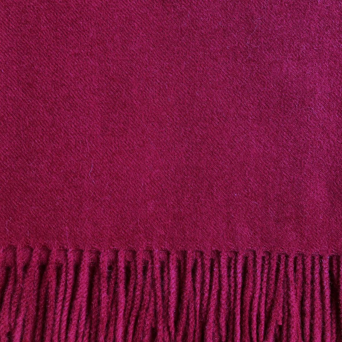 Close up of burgundy woven fabric with fringe on the bottom.