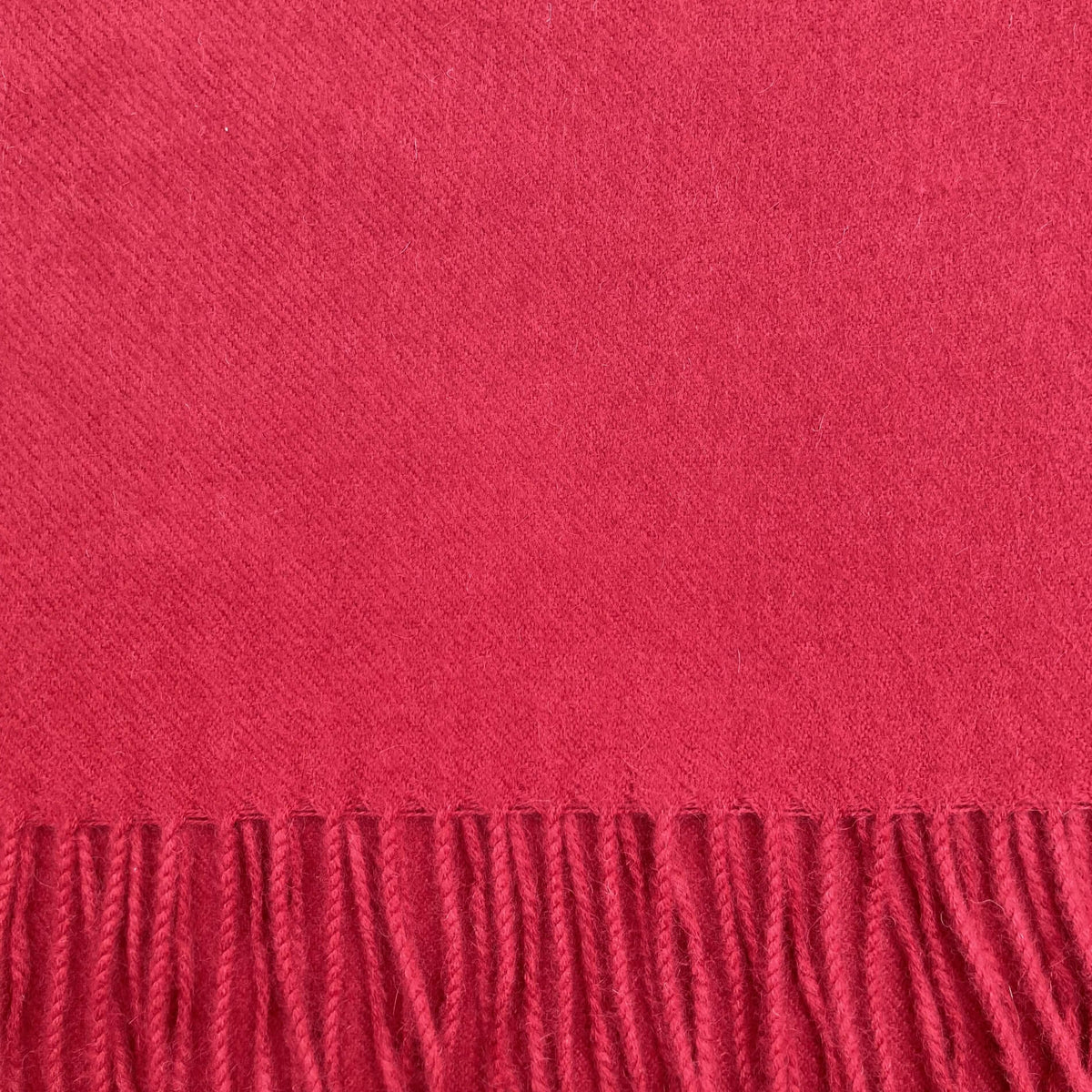 Close up of bright red woven fabric with fringe on the bottom.