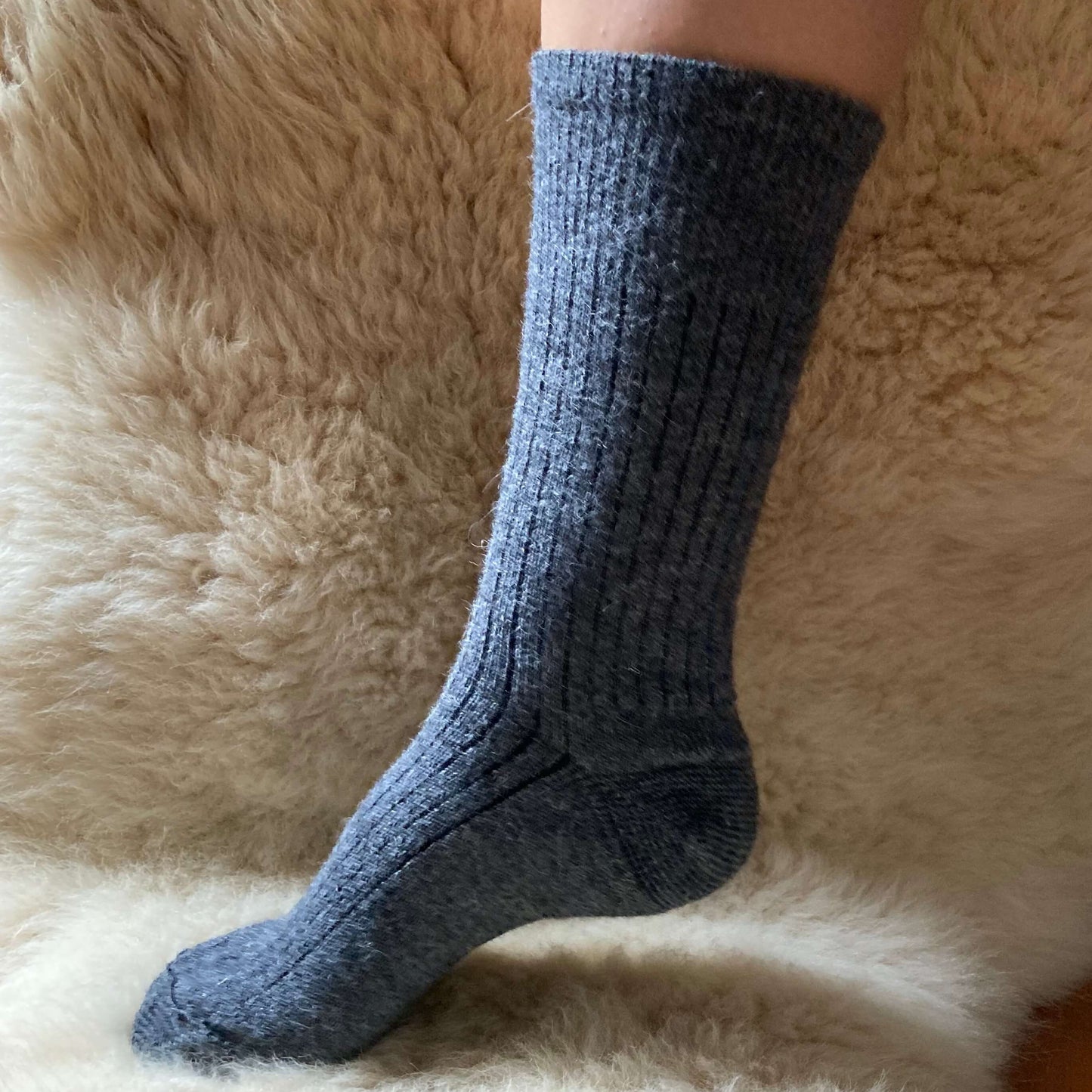 Grey ribbed alpaca sock on a fluffy beige surface