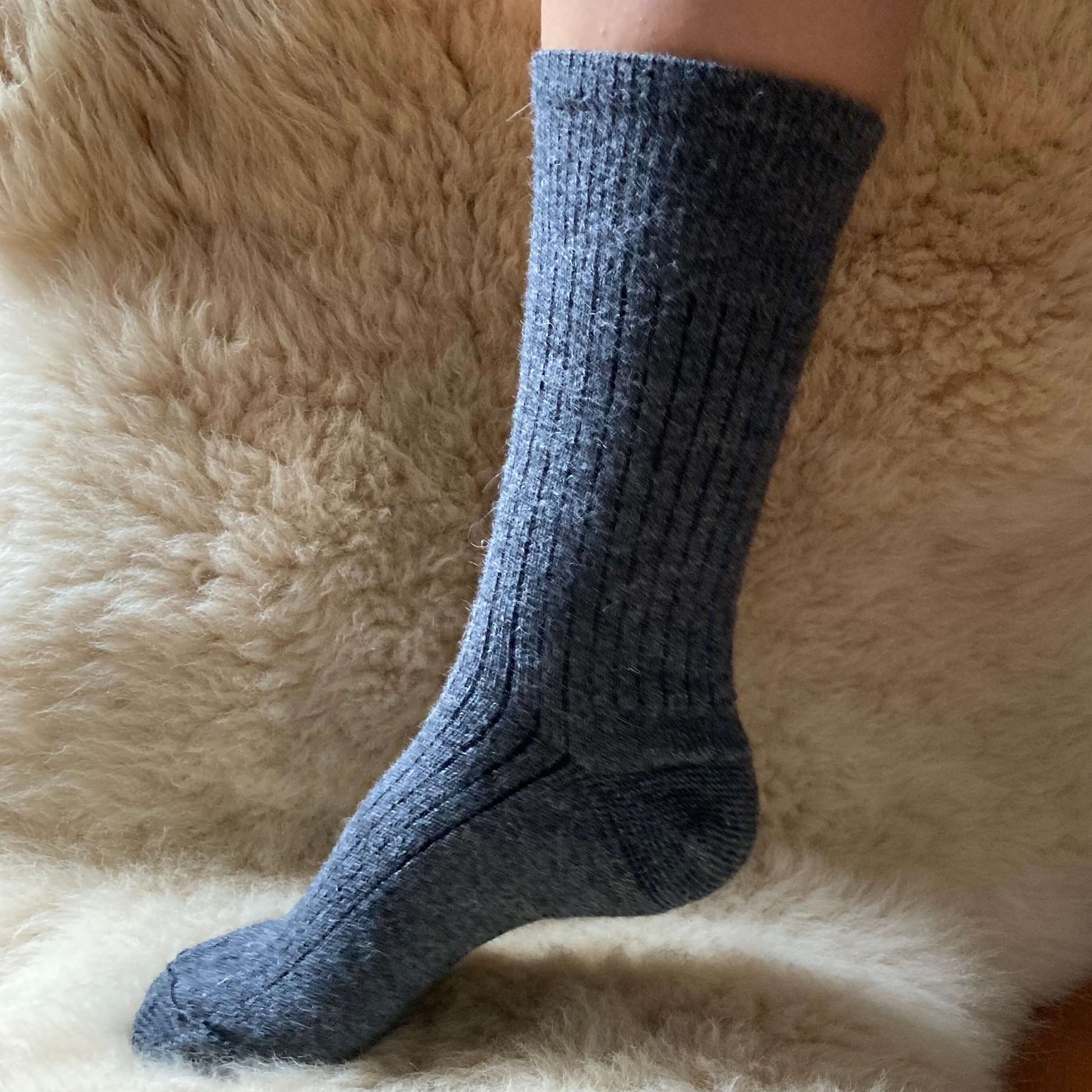 Grey ribbed alpaca sock on a fluffy beige surface