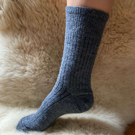 Grey ribbed alpaca sock on a fluffy beige surface