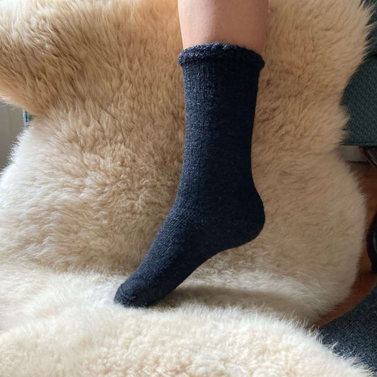Heavy weight charcoal gray alpaca sock on a fluffy beige surface