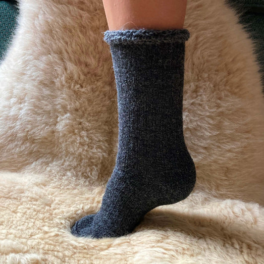 Heavy weight grey alpaca sock on a fluffy beige surface