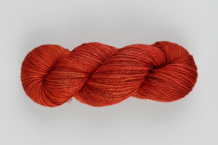 Variegated Burnt Orange skein of yarn on a white background