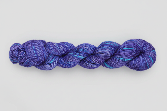 Variegated Blue skein of yarn on a light gray background