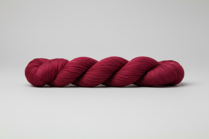Burgundy skein of yarn on a light gray background