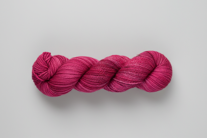 Variegated Wine and Roses Pink skein of yarn on a light gray background