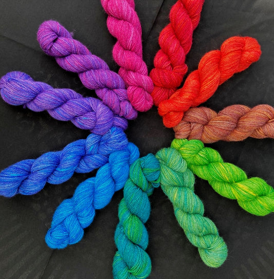 Colorful yarn skeins arranged in a circular pattern on a black background
